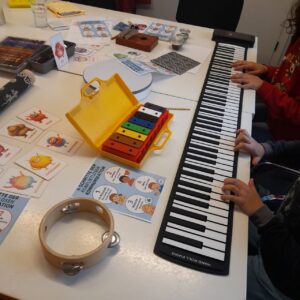 Vorbereiteter Raum für Musiktherapie-Gruppensitzung bei Farbe und Klang Leipzig, mit Gitarre, Boomwhackers, Rollpiano und Klavier im Hintergrund.