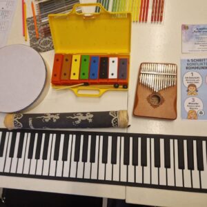Nahaufnahme einer akustischen Gitarre und bunten Boomwhackers auf einem Tisch, bereit für eine musiktherapeutische Sitzung in Leipzig.